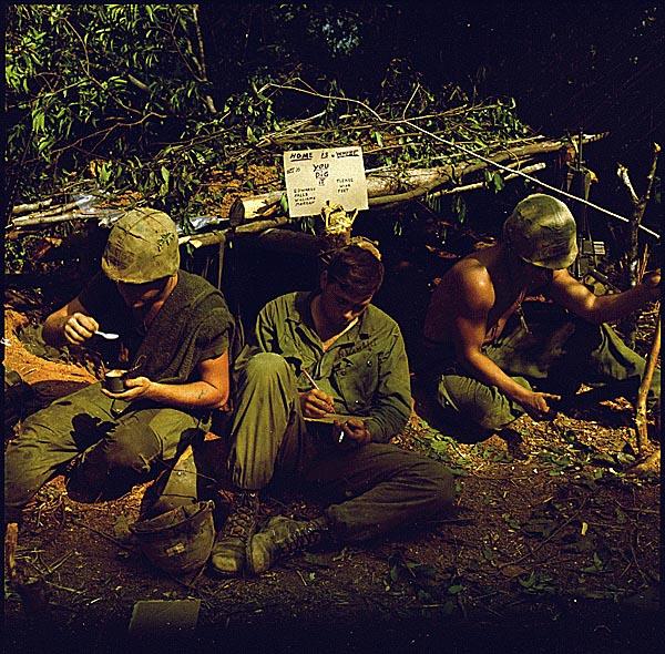 American soldiers in Vietnam sit in front of a fighting bunker bearing the handwritten sign 