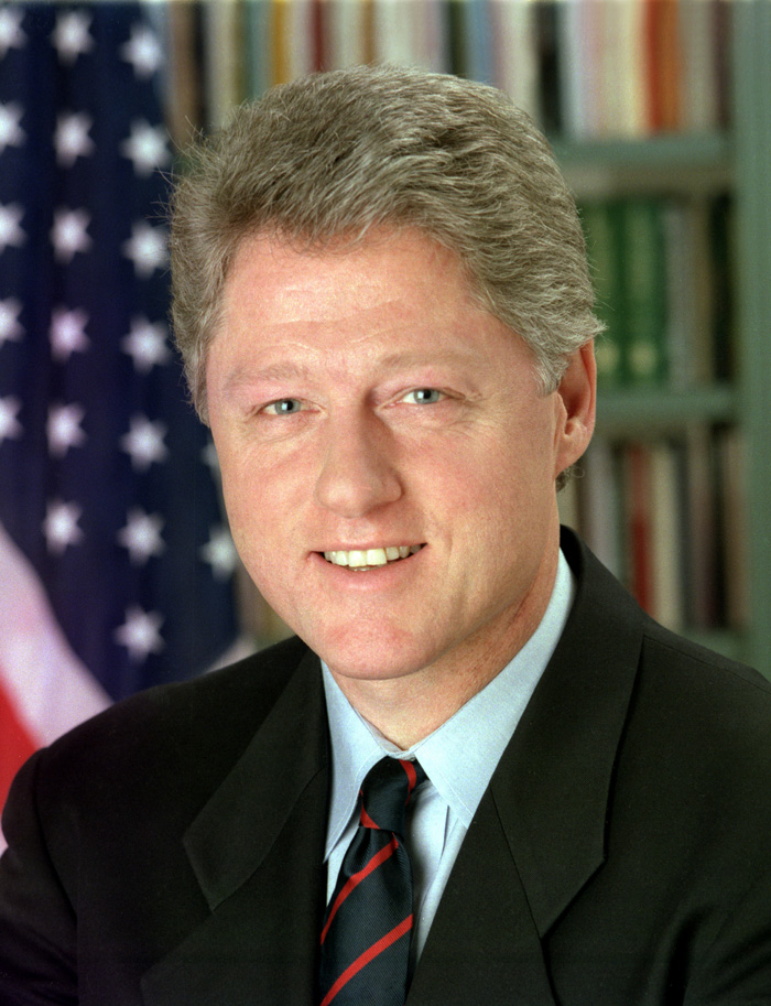 Bill Clinton  smiling wearing a suit and tie.