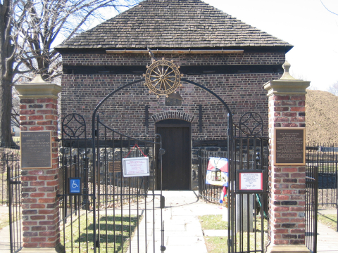 Brick building with large wooden door behind gate