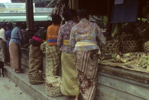Women stand by platform preparing offerings for large cremation ceremony