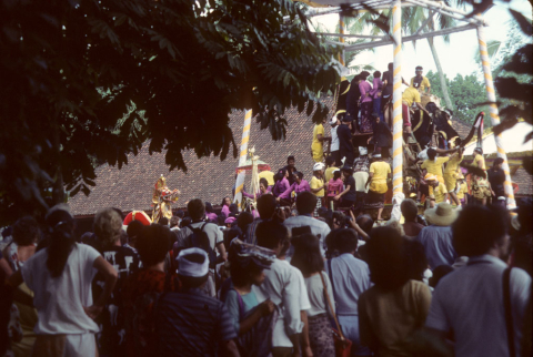 Crowd watches as offerings are placed with corpse in hollow bull figure at cremation