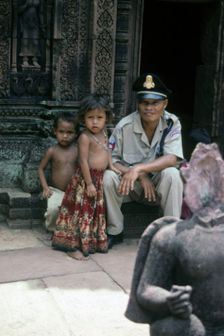 Uniformed guard sits with two small children at Banteay Srei Temple