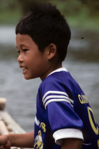 Portrait of smiling boy in near profile wearing blue sports shirt at Hoa Lu