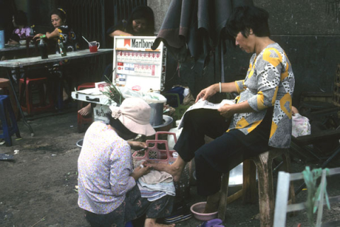 Woman outside street cafe receives pedicure in Ho Chi Minh City's Chinatown