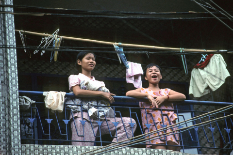 Woman and girl with laundry on balcony in Ho Chi Minh City's Chinatown