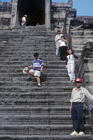 Several people stand along the steps to the central tower at Angkor Wat