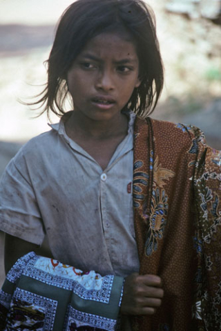 Portrait of girl holding two textiles for sale at Siem Reap